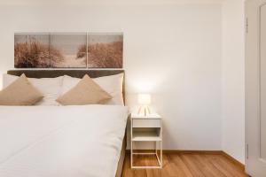 a white bedroom with a bed and a nightstand with a lamp at SOHO A !Gratis parken, Free Parking! in Kreuzlingen +4 photos