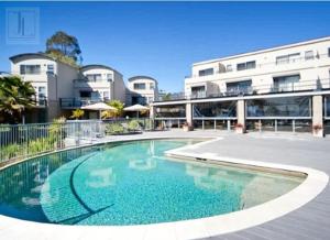 a swimming pool in front of a building at Ground Floor Spa Apartment Corrigans Cove in Batehaven