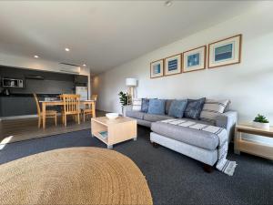 a living room with a couch and a table at Ground Floor Spa Apartment Corrigans Cove in Batehaven +3 photos