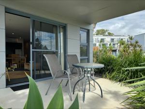 a patio with chairs and a table and some plants at Ground Floor Spa Apartment Corrigans Cove in Batehaven