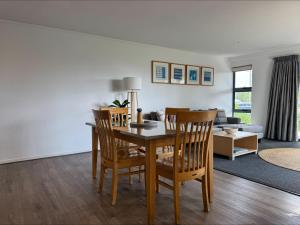 a dining room and living room with a table and chairs at Ground Floor Spa Apartment Corrigans Cove in Batehaven