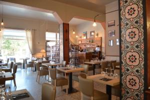 a restaurant with tables and chairs in a room at Hôtel le Grillon in LʼÎle-Rousse