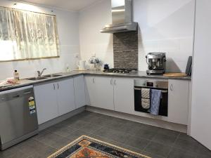 a kitchen with white cabinets and a sink and a stove at York - Mulyinjinin Valley Cottage in York