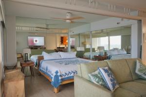 a bedroom with a bed and a couch and a mirror at Ilikai Hotel Condo with Kitchen and Ocean View in Honolulu