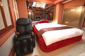 a bedroom with a bed and a chair in it at ホテルサティス伊勢店 in Ise