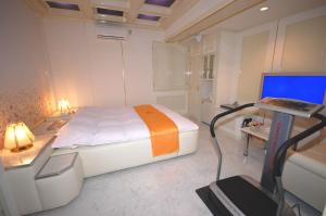a bedroom with a bed and a desk with a computer at ホテルサティス伊勢店 in Ise