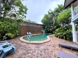 a swimming pool with two chairs in a backyard at Flying Fish House in South Mission Beach