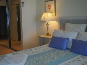 a bedroom with a bed with blue pillows and a lamp at BHA 1 Beachfront Haven fullhouse in Mission Beach