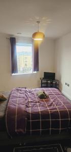 a bedroom with a large bed with a purple blanket at Excellent 2 bedroom Apartment- great Connectivity to central london in Barking
