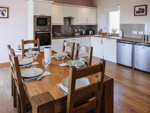 a kitchen with a wooden table with plates and wine glasses at Heron View in Kirkcudbright