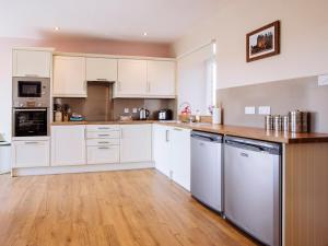 a kitchen with white cabinets and a wooden floor at Heron View in Kirkcudbright +9 photos