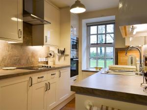 a kitchen with white cabinets and a sink and a window at The Stable - 31240 in Kilmartin