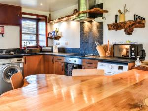 a kitchen with a wooden table and a counter top at Ochiltree Cottage - Uk7781 in Newton Stewart