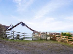 a barn with a wooden fence next to it at Dondies House in Kilchoan