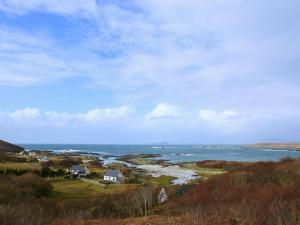 a house on a hill next to a body of water at Dondies House in Kilchoan +2 photos