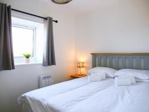 a white bed with two pillows and a window at Dondies House in Kilchoan