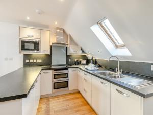 a kitchen with white cabinets and a skylight at 23 Mount Brioni in Downderry +14 photos
