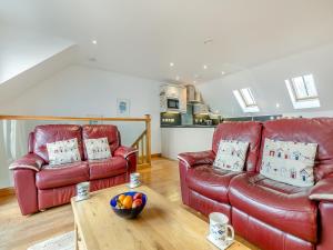 a living room with two red leather couches and a table at 23 Mount Brioni in Downderry