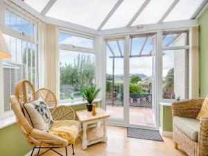 a conservatory with chairs and a table and windows at Anchors Away - 29566 in Blue Anchor
