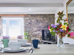 a table with plates and a vase of flowers on it at Imperial Apartment in Oban