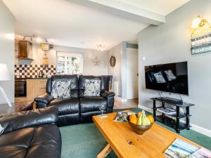 a living room with a leather couch and a table at 6 Mount Brioni in Downderry