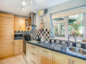 a kitchen with wooden cabinets and a sink and a window at 6 Mount Brioni in Downderry +7 photos