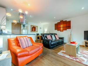 a living room with an orange couch and a kitchen at 21 Mount Brioni in Downderry