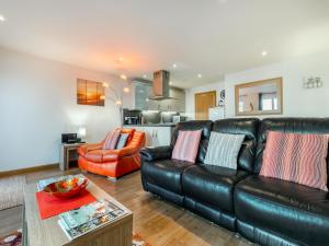 a living room with a black leather couch and an orange chair at 21 Mount Brioni in Downderry