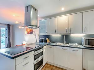 a kitchen with white cabinets and a sink and a microwave at 21 Mount Brioni in Downderry +15 photos