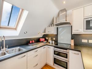 a kitchen with white cabinets and a sink and a window at 18 Mount Brioni in Downderry