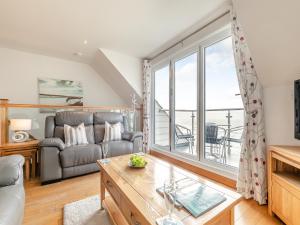 a living room with a couch and a large window at 18 Mount Brioni in Downderry
