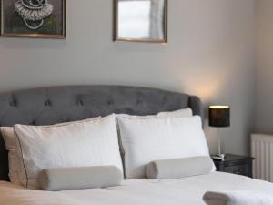 a bed with white pillows and a gray headboard at Coastal Gem - Uk2773 in Llandudno