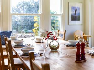 a wooden table with glasses and a vase with flowers on it at Downedge in Brading
