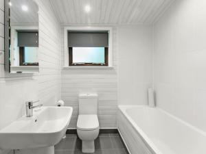 a white bathroom with a sink and a toilet and a tub at Ben Klibreck in Kinloss +3 photos