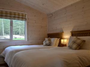 two beds in a room with wooden walls at Ben Klibreck in Kinloss