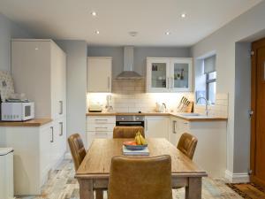 a kitchen with a wooden table and chairs at The Corn Store in Malpas
