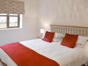 a bedroom with a bed with two red pillows at The Corn Store in Malpas