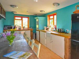 a kitchen with blue walls and a table with flowers at The Timber Store in Hardham +20 photos