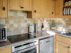 a kitchen with wooden cabinets and a counter top at Stearn Cottage-17917 in Langham
