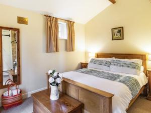 a bedroom with a bed and a vase of flowers on a table at Stearn Cottage-17917 in Langham +17 photos