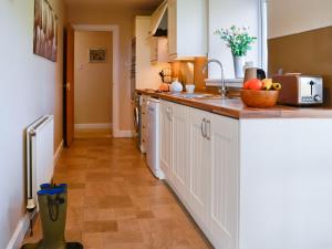 a kitchen with white cabinets and a counter top at The Byre in Kirkcudbright