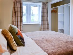 a bedroom with a bed with pillows and a window at The Byre in Kirkcudbright +11 photos