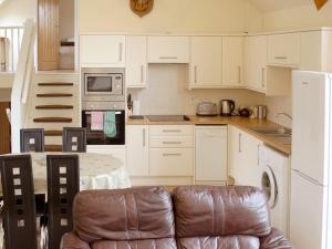 a kitchen with white cabinets and a table with a couch at The Byre - Uk7790 in Milton of Auchinhove