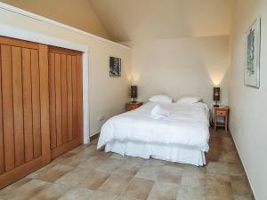 a bedroom with a white bed and a wooden door at The Byre - Uk7790 in Milton of Auchinhove