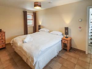 a bedroom with a large white bed and a night stand at The Byre - Uk7790 in Milton of Auchinhove +2 photos