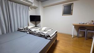 a bedroom with a bed and a desk and a window at MORI Apartment Near namba in Osaka