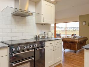 a kitchen with a stove top oven next to a couch at Ford Cottage in Banchory