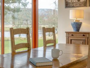 a table with two chairs and a coffee cup on it at Ford Cottage in Banchory