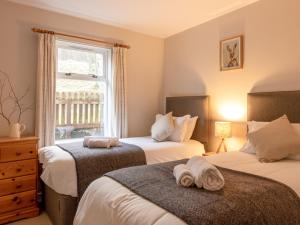 a bedroom with two beds and a window at Ford Cottage in Banchory