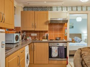 a small kitchen with wooden cabinets and a bed at The Garden Flat in Torquay